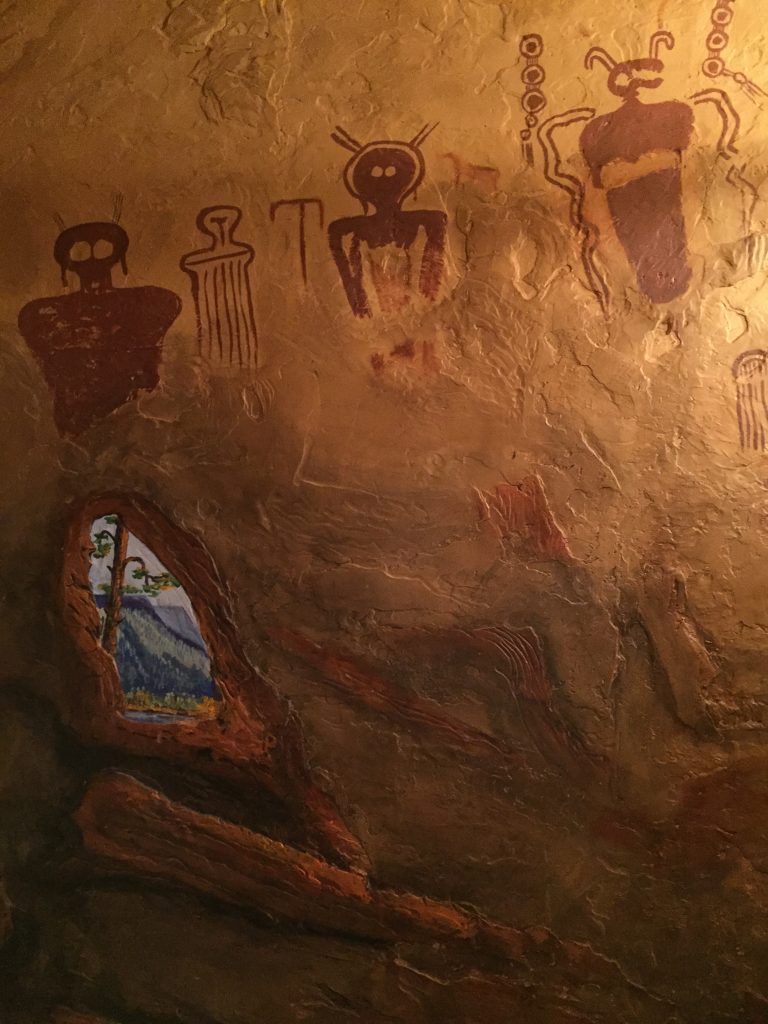 Brown Cave painted on wall with Petroglyphs and window with blue sky